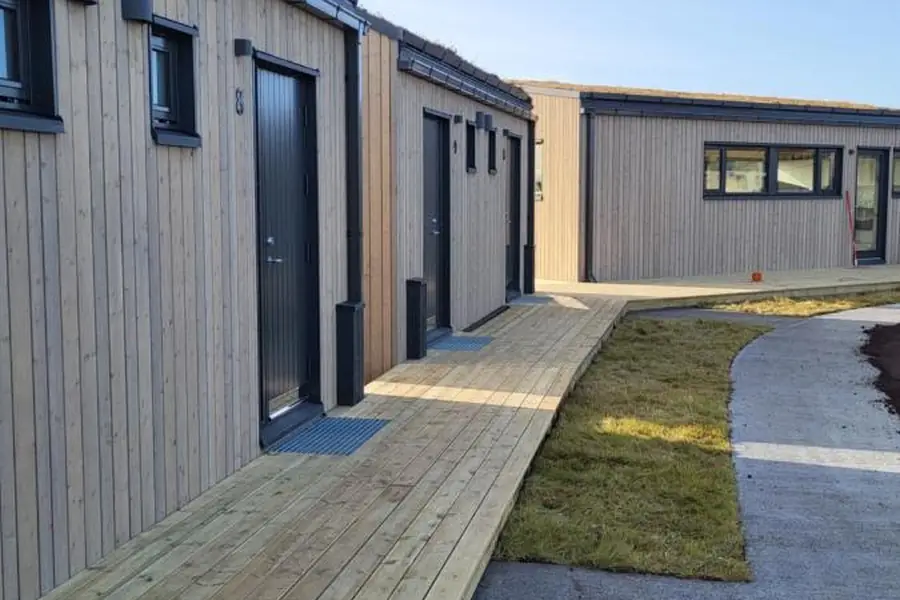 Row of timber cabins at Landbrot Guesthouse with the wooden walkway, in Kirkjubæjarklaustur